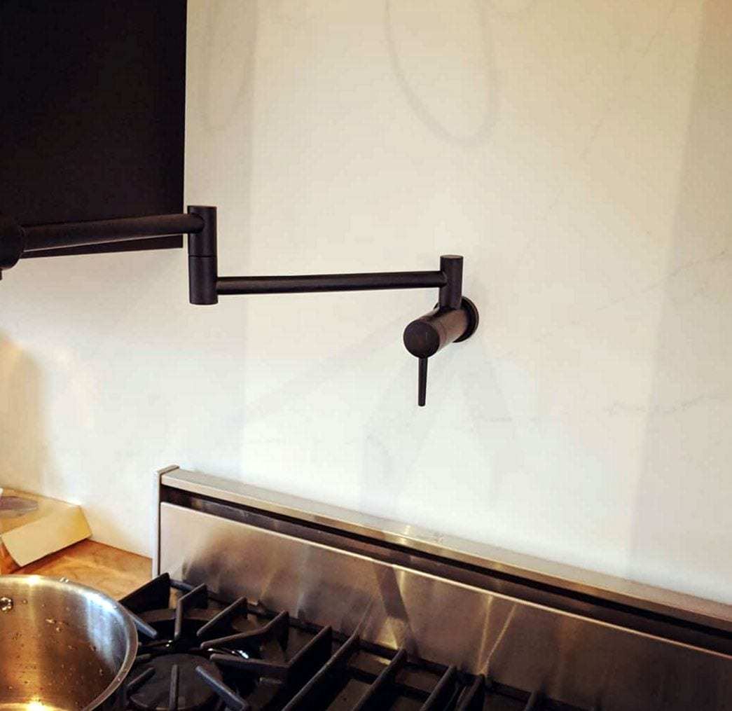 Matte black wall-mounted pot filler faucet folded over a stainless range