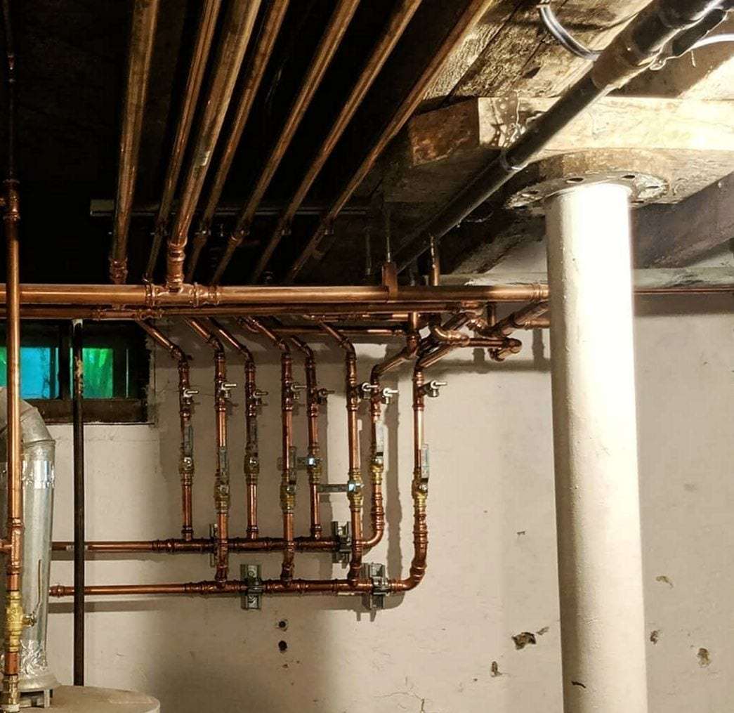 New copper supply lines with shutoff valves branching across an older basement wall