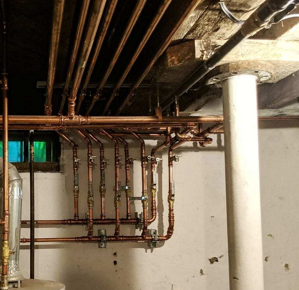 New copper supply lines with shutoff valves branching across an older basement wall