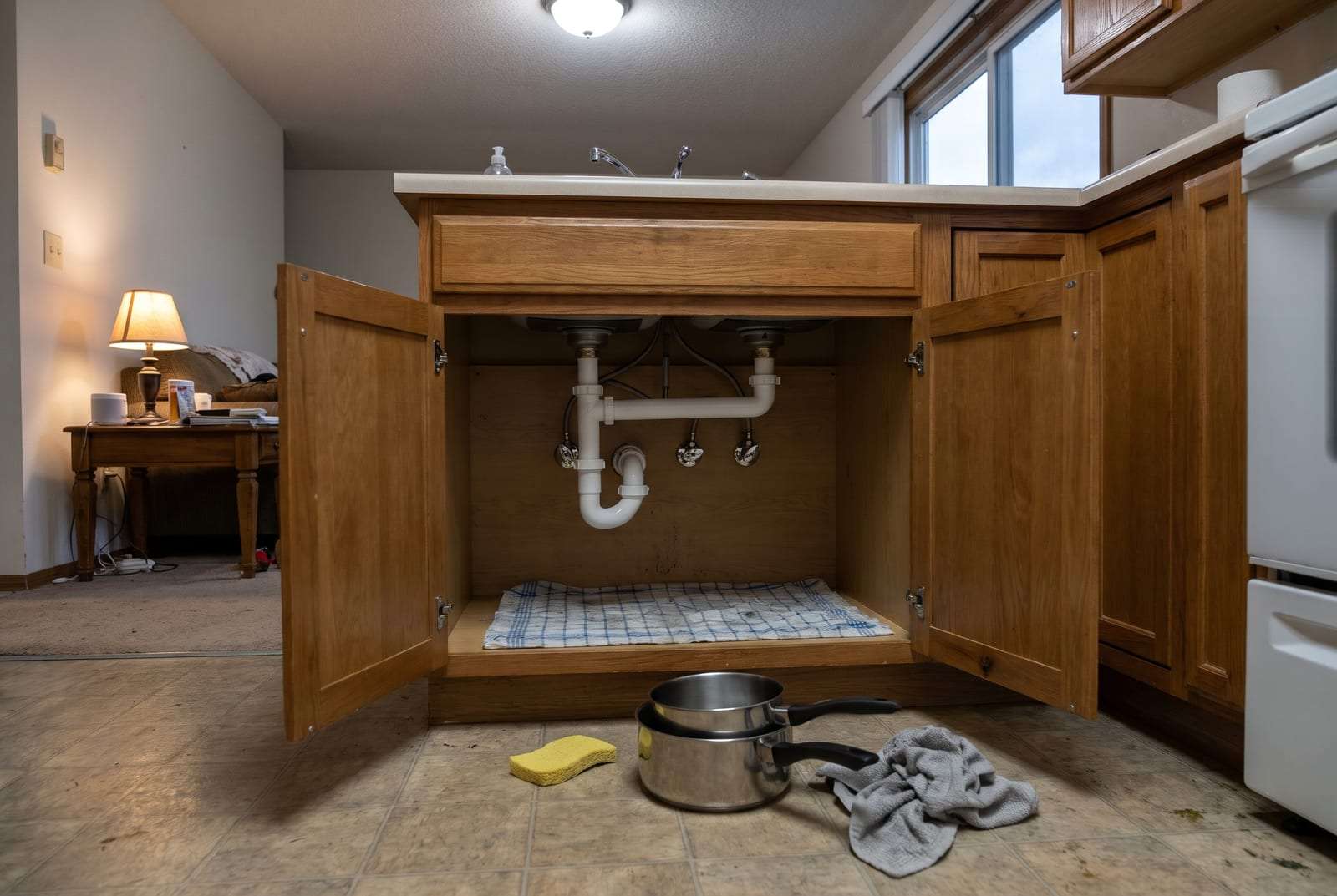 New drain trap and shut-off valves under a kitchen sink, the cabinet doors open